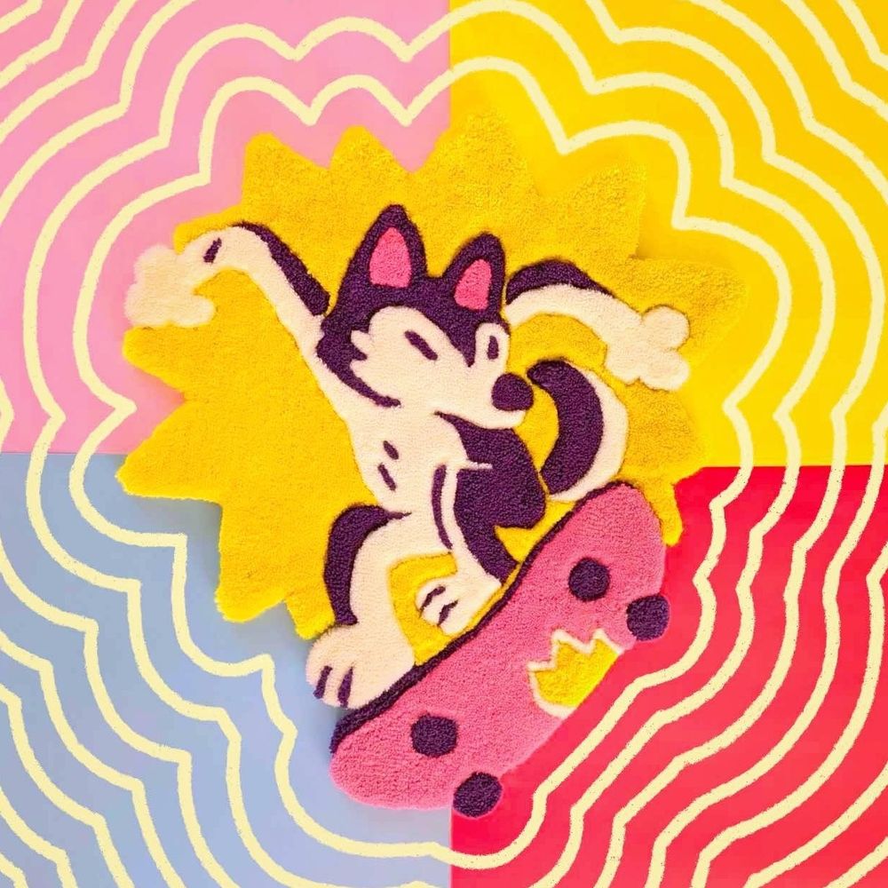 A photo of a hand-made rug, depicting a cartoon-styled husky doing a kickflip on a skateboard. There's a yellow "explosion-style" spikey shape placed around the husky, to make the overall piece feel more vibrant and dynamic.