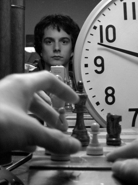 Me taking a photo of my mirror -- my hands "play" chess with a large clock. 