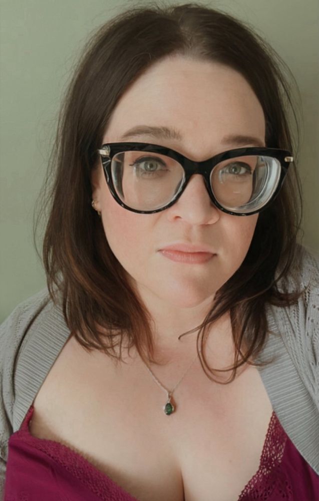 Selfie of a woman with medium length hair and black plastic frame glasses.