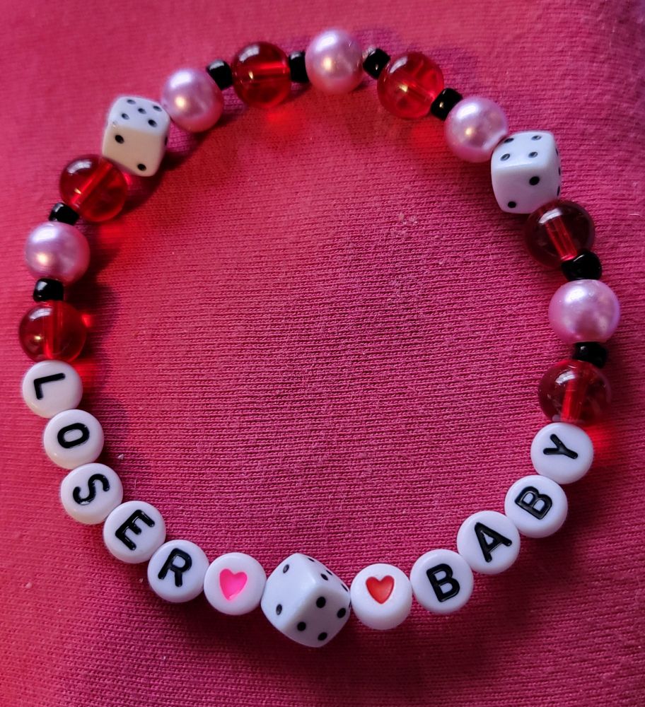 A Hazbin Hotel inspired bracelet, it has the quote "Loser baby" from a song that played in the animated series.