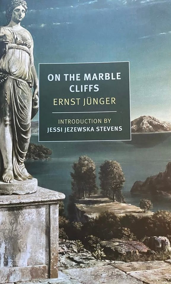 Cover of the novel on the marble cliffs by Ernest junger. A statue on the left, a lake in the background, mountains beyond.