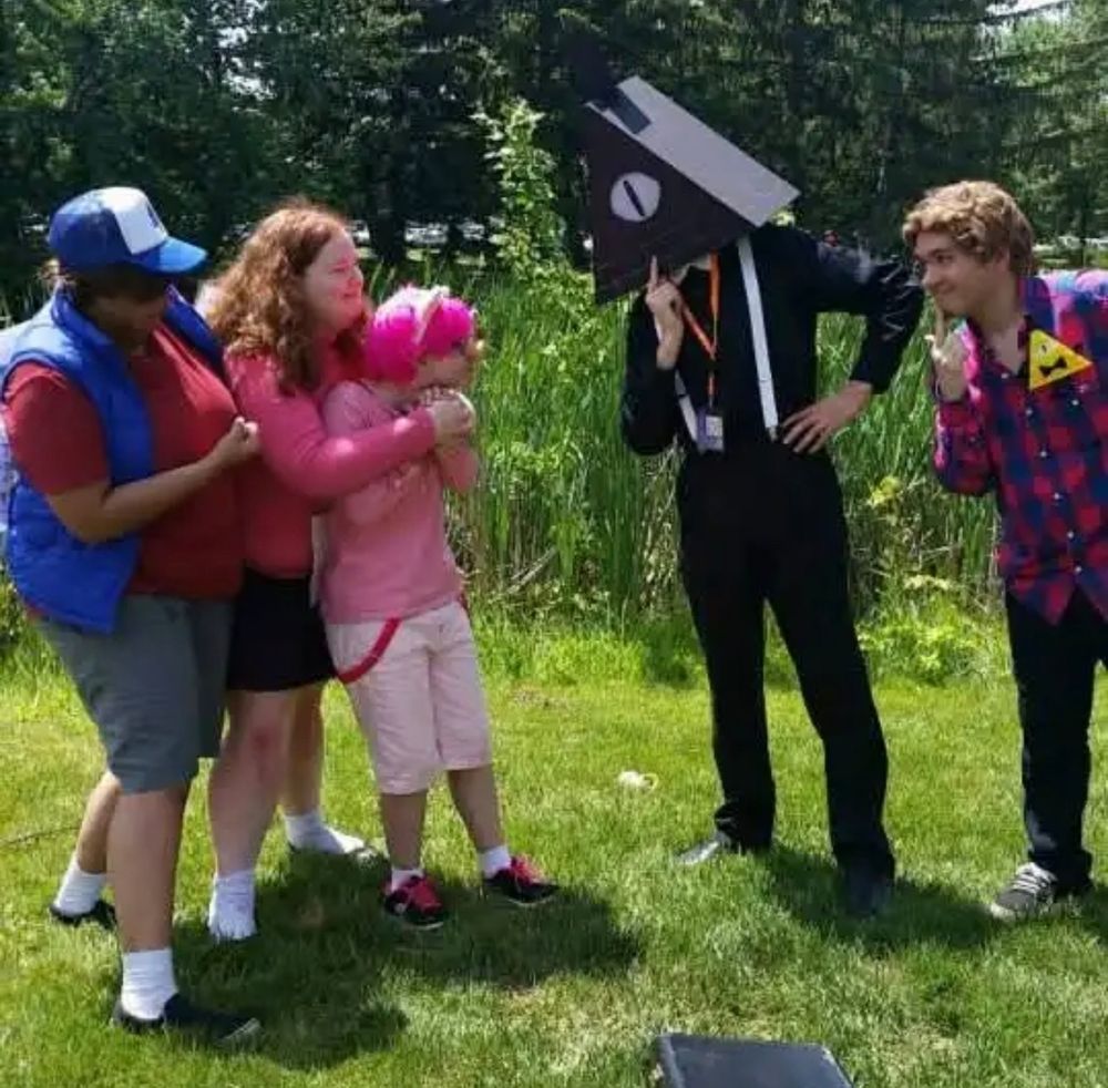 Charley dressed as Alex Hirsch and someone else dressed as Bill looming over Dipper, Mabel, and Waddles cosplayers