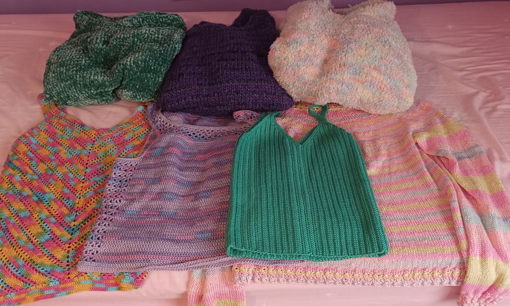 Foto en la que se muestran 3 jerseys de lana gorda, 3 camisetas de tirantes y un suéter finito, todo ello de varios colores.