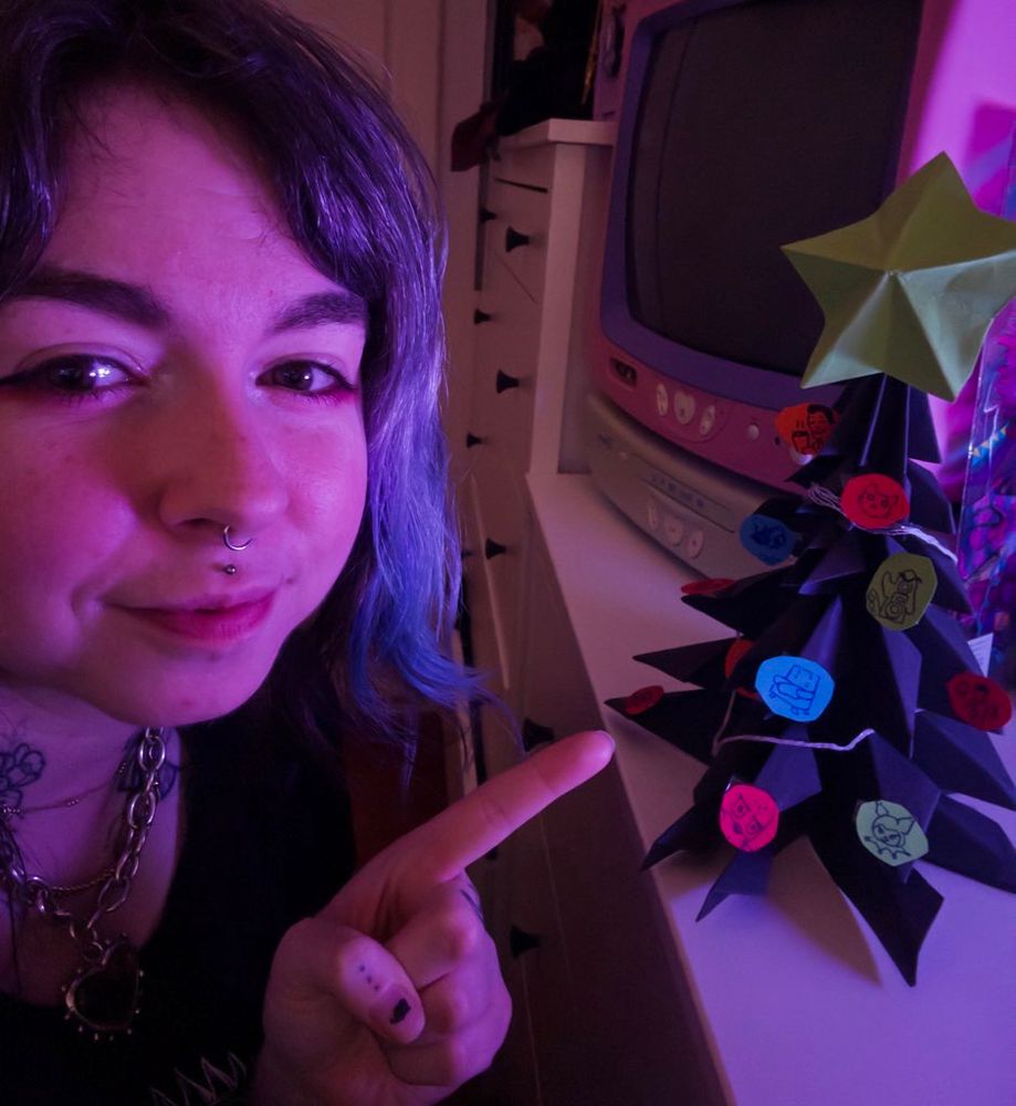 Connie posing with her charity Christmas tree with drawings of donors.