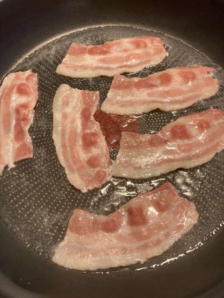 Bacon i vatten i en stekpanna.
