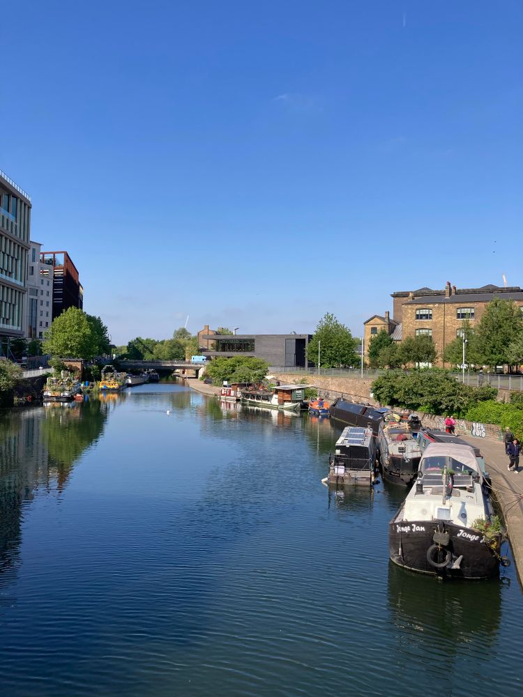 Regent’s Canal on a sunny day. Barges, trees and waterfowl are visible.
