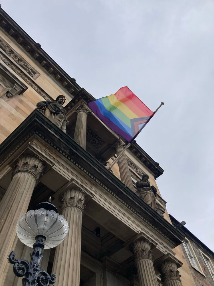 The Progress Pride flag flies outside the main entrance.