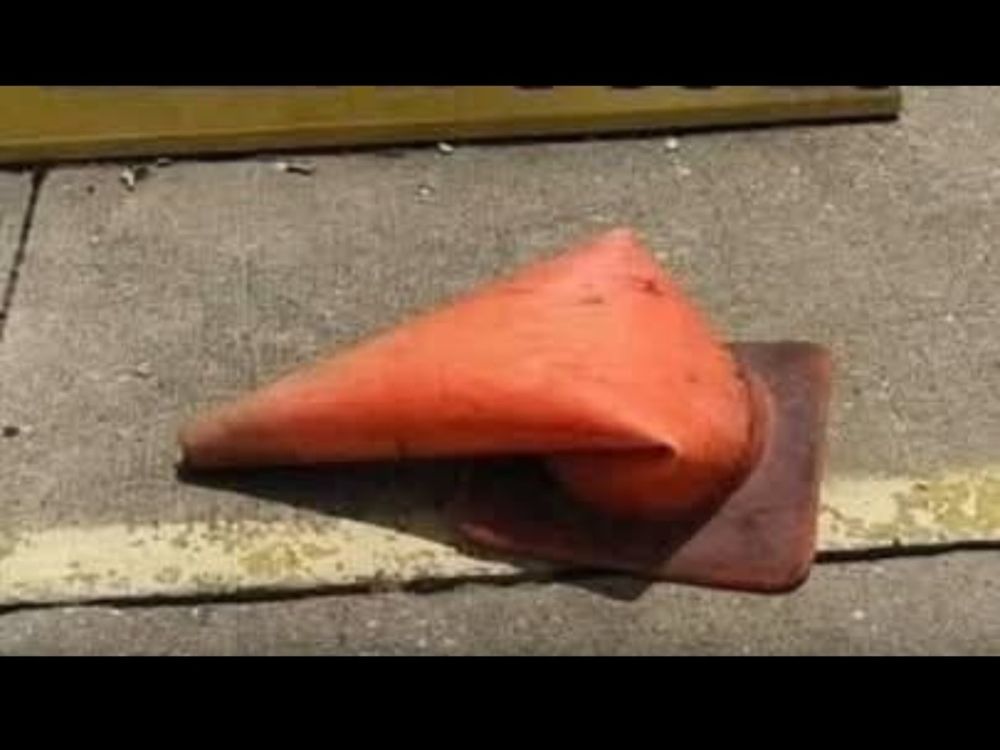 A bent orange traffic cone.
Caption: So hot today, our state flower melted.