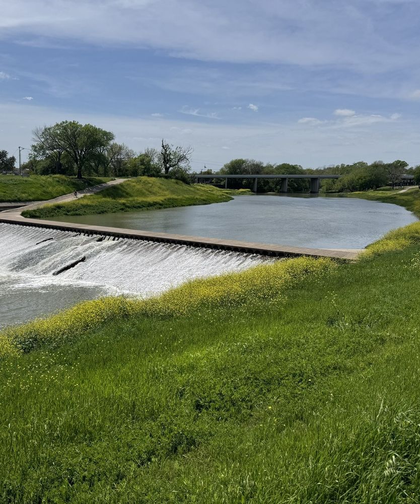 a river flows over a small dam in a park in Fort Worth, Texas