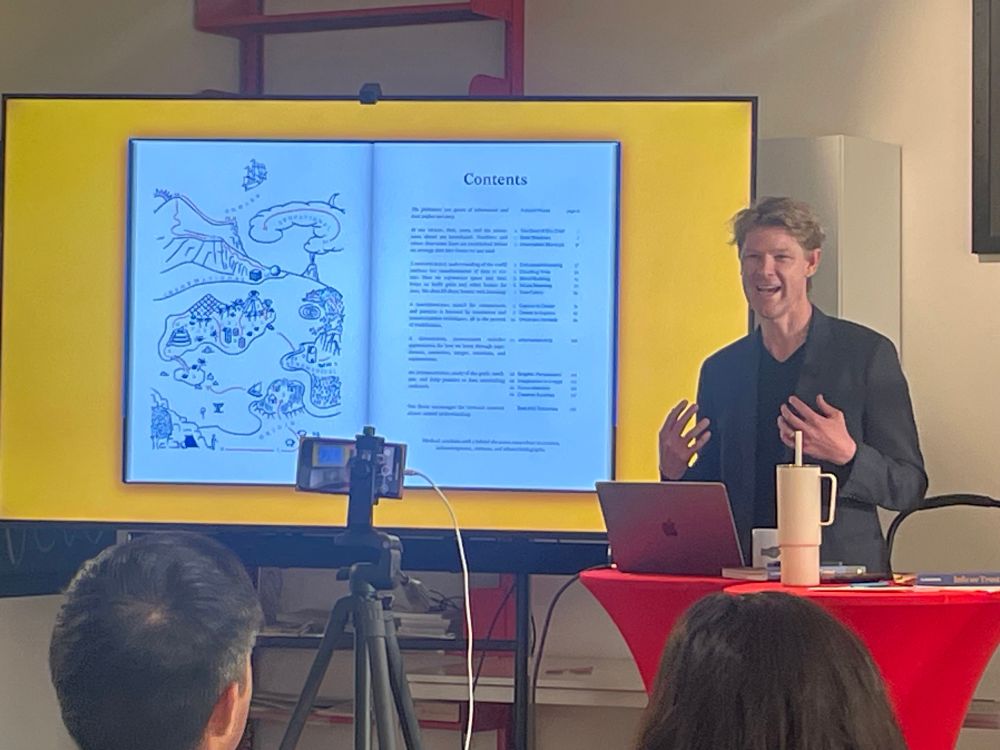 Photo of Rj talking in front of projected image of his book 