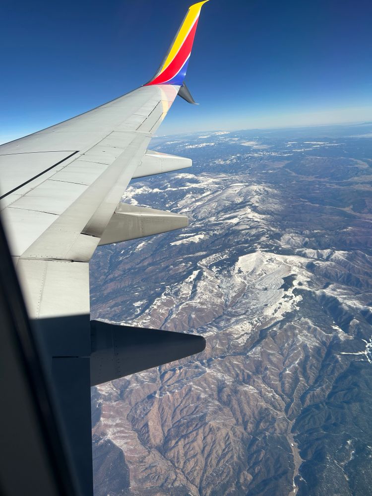 A plane wing crosses over mountains 