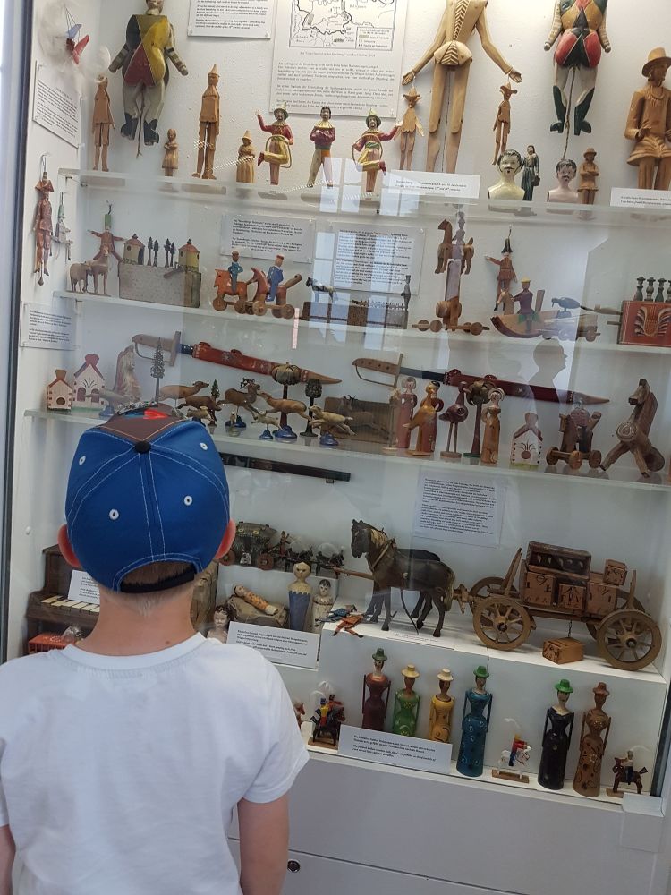 Gutt med caps ser på ei samling gamle leiker