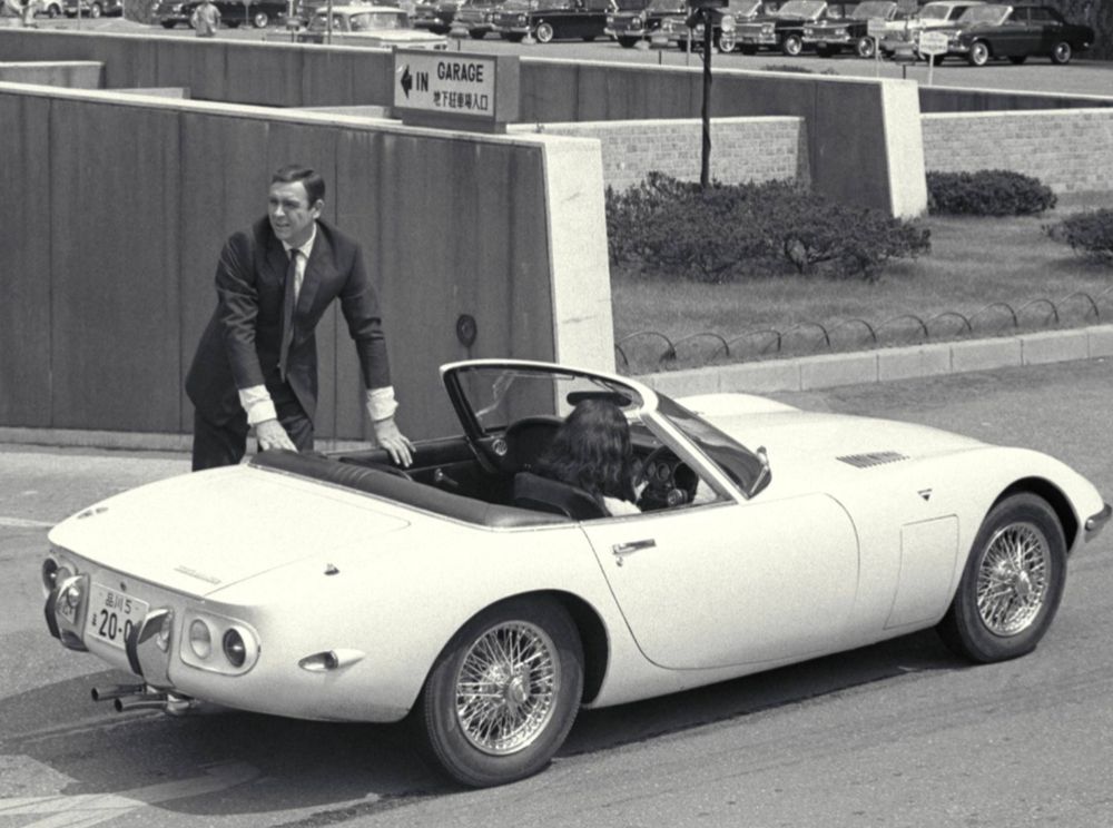 Sean Connery as James Bond standing next to a custom roadster version of the Toyota 2000GT as seen in You Only Live Twice 