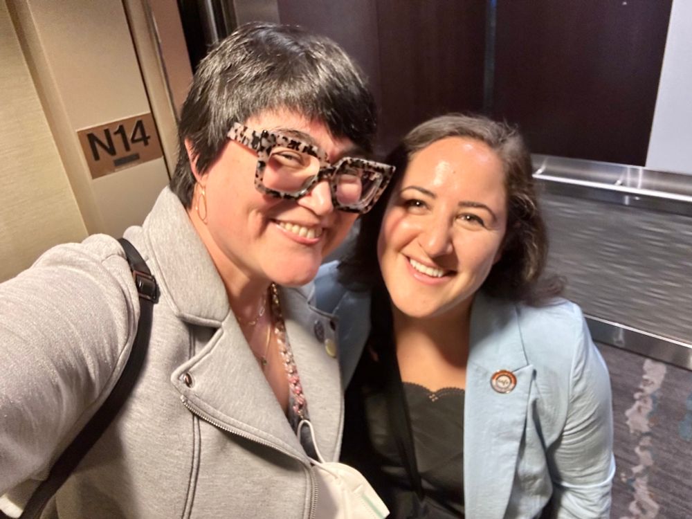 Two women taking a selfie while smiling in the door of an elevator bc we forgot to take a photo in a more picturesque setting 