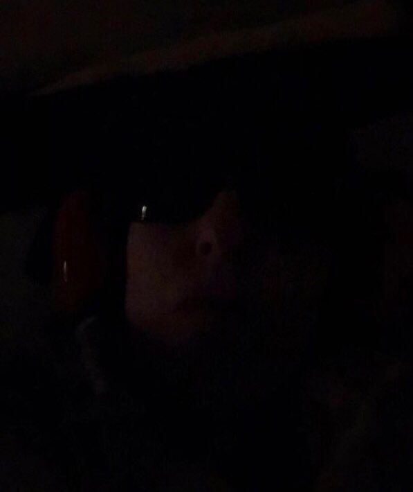 Very ill woman in bed in dark room with sunglasses and ear defenders on to lower so sort overload 