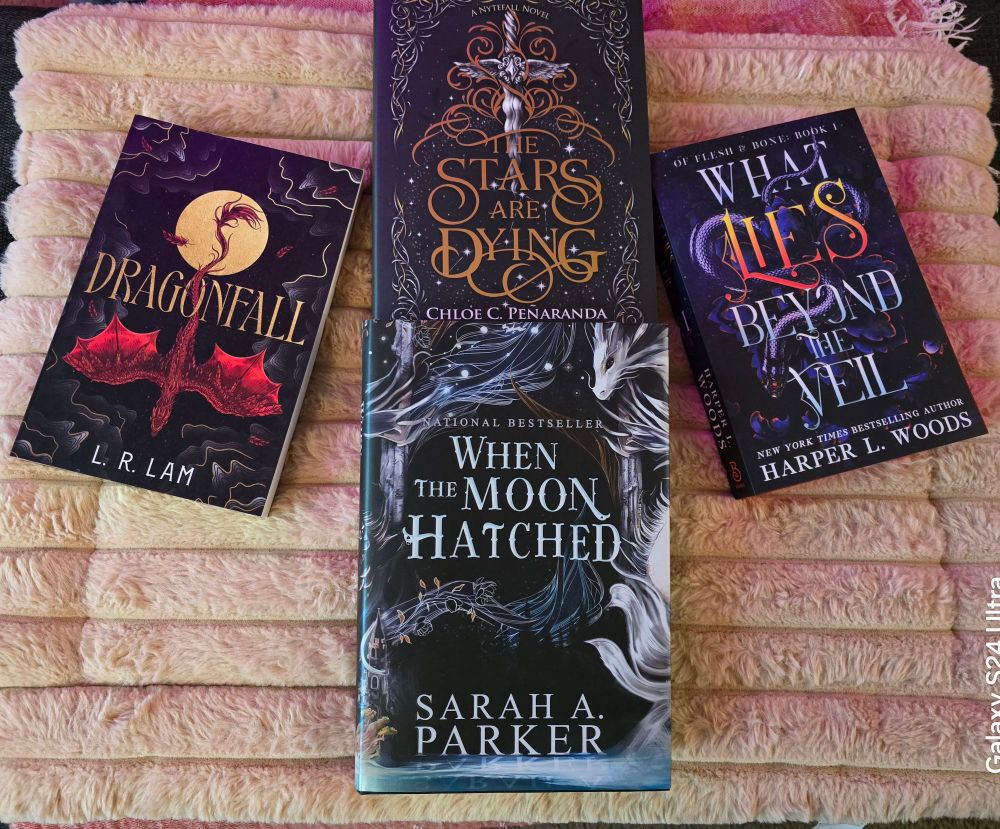 A picture of four fantasy novels, "Dragonfall" by L.R. Lam, "The Stars Are Dying" by Chloe C. Peñaranda, "What Lies Beyond The Veil" by Harper L. Woods, and "When the Moon Hatched" by Sarah A. Parker.
