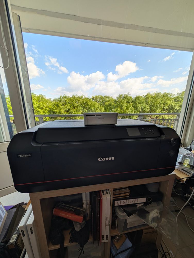 Photo comparing the size of the tiny Canon Selphy CP1000 vs giant Canon ImagePrograf Pro-1000