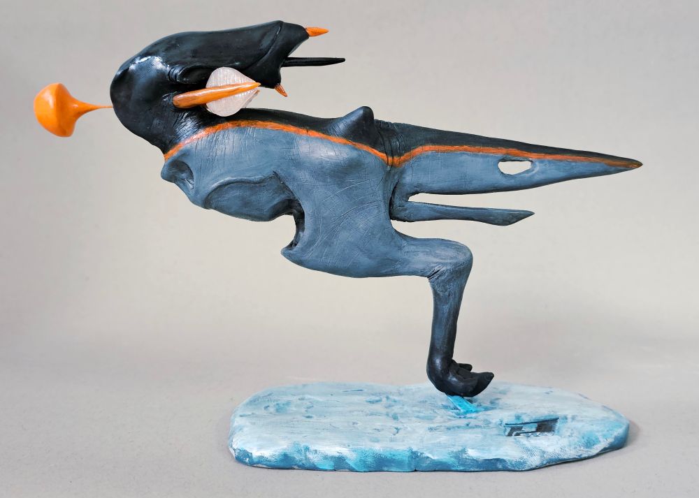 Sculpture of a monopedal alien in mid hop. Its body resembles that of a theropod dinosaur with no arms and a single leg that starts on either side of the body and meets at the knee. It has a long, swept back head with no eyes.