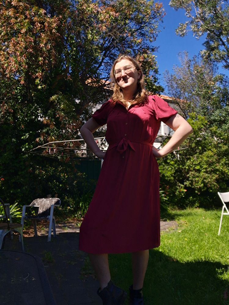 Four selfies of Jasmine in her backyard wearing a red dress which buttons up from the waist and has a collar. It is crimson, cozy and cute.  