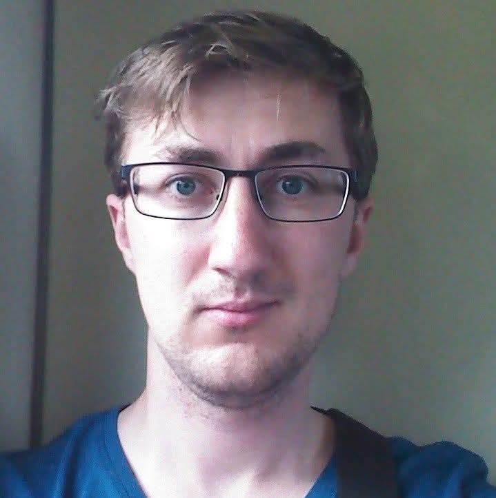 Jasmine in 2015 with short hair, square glasses and some awful stubble, looking kinda empty in the eyes.  