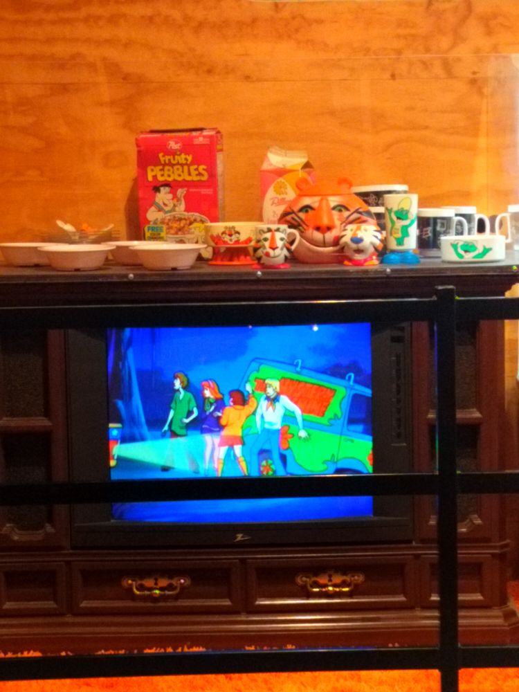Old console tv with cereal bowls on top. The tv is playing Scooby Doo