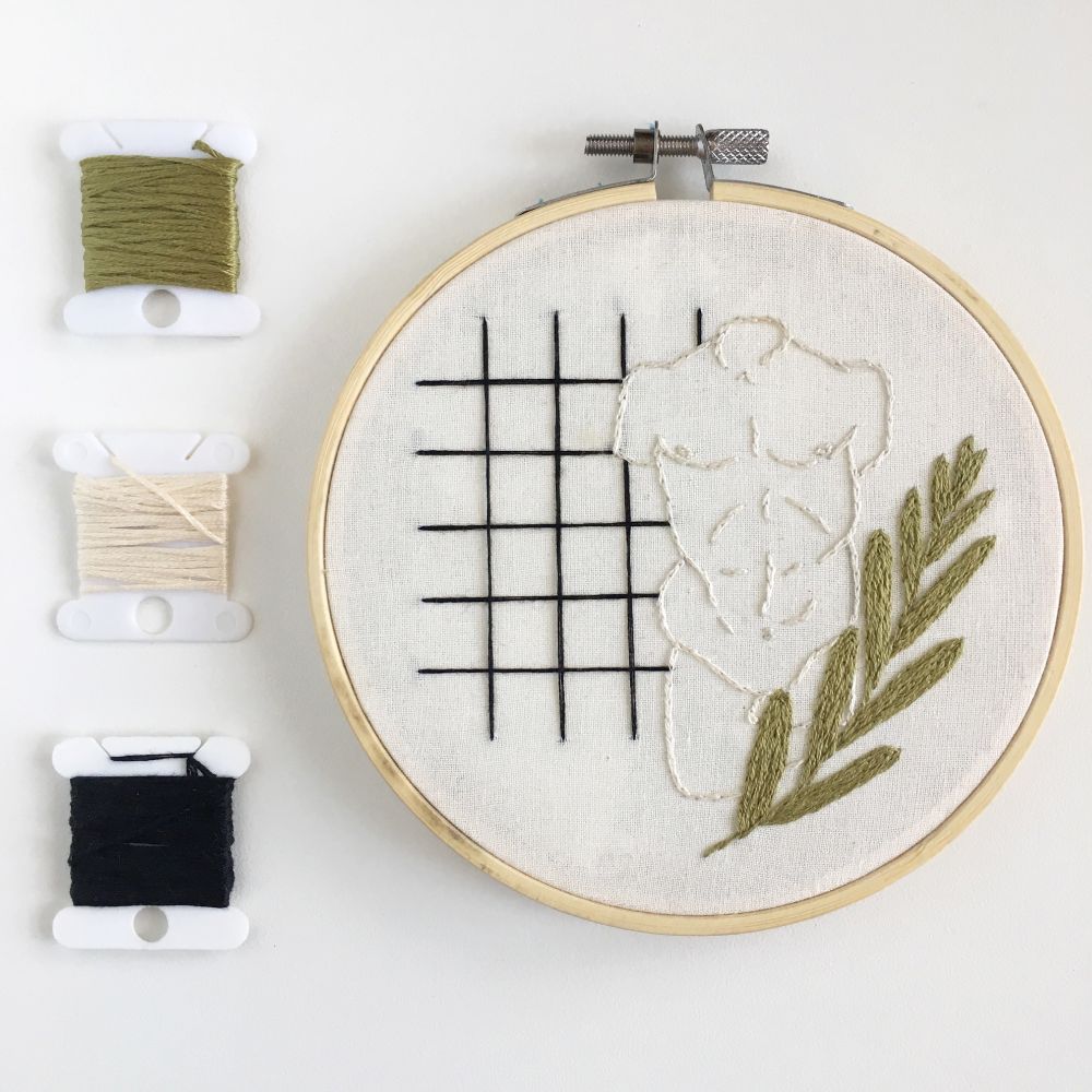 an embroidery of a male chest with an olive branch and a grid background on white fabric