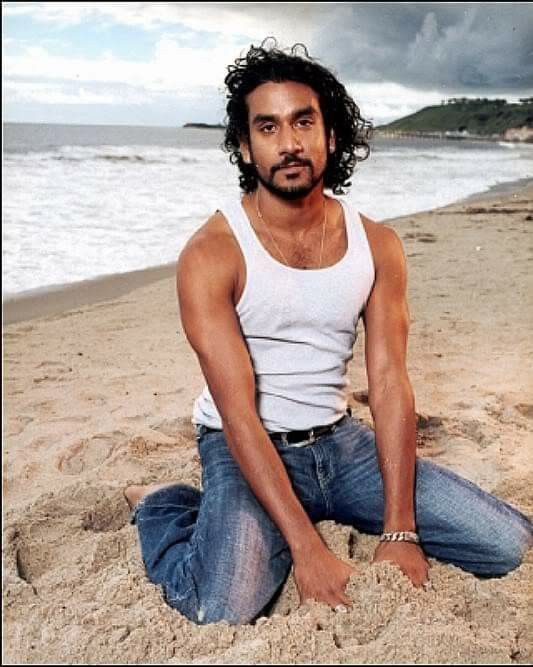 Photo promotionnelle pour la série Lost. Sayid Jarrah (Naveen Andrew) est a genoux dans le sable, la mer derrière lui. Il regarde vers l'objectif.