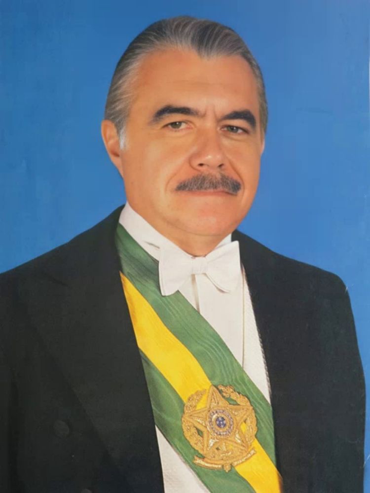 a man with a mustache is wearing a green and yellow sash with the emblem of brazil on it