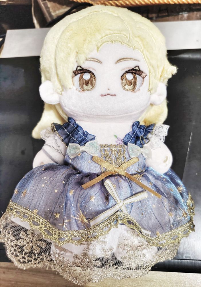 Dion Lesage cotton doll wearing a bkue, sparkly dress with gold lace at the hem. 