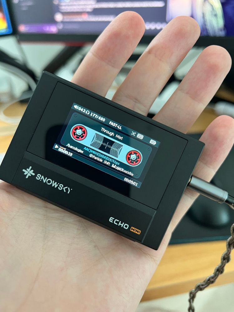 A small black mp3 player shaped like an old tape cassette. The screen in the middle shows a fake tape UI with playback information