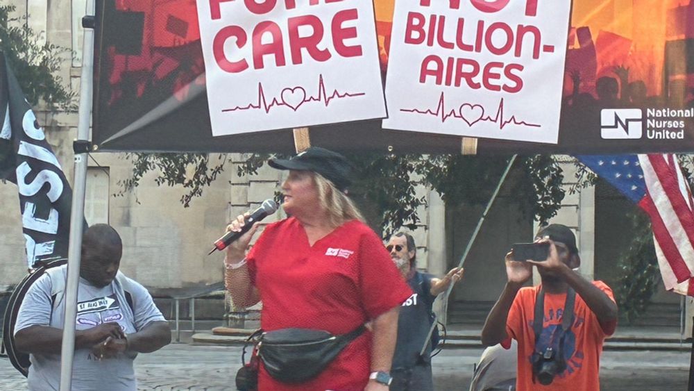 Individuals at a protest with signs reading 