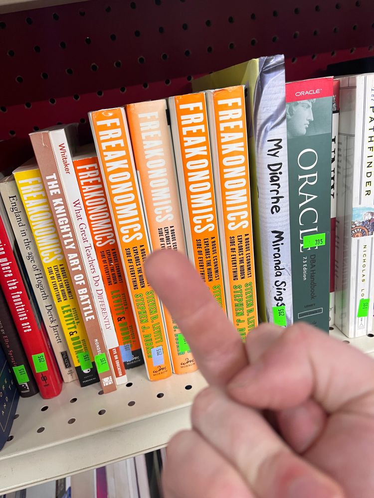 A picture of a hand giving the middle finger to several copies of the book Freakonomics