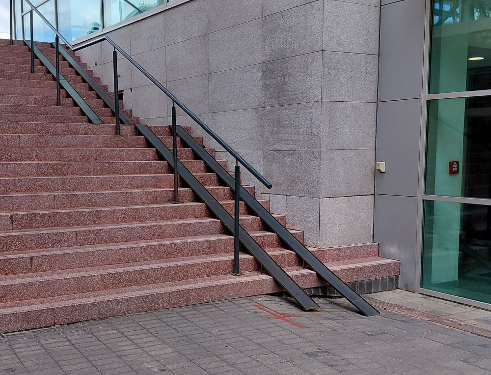 Pair of steel Ramps fitted to series of red stone brick steps. Inner ramps is several inches shorter than the other, approximately 2cm above ground 