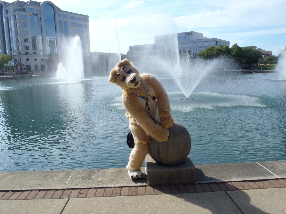 Goldy on a big concrete ball in front of a fountain lake