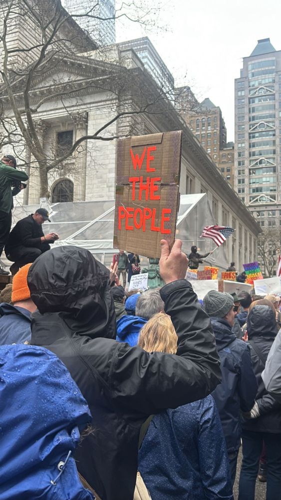 A picture of a protest scene focused on a person holding a sign that reads “we the people”