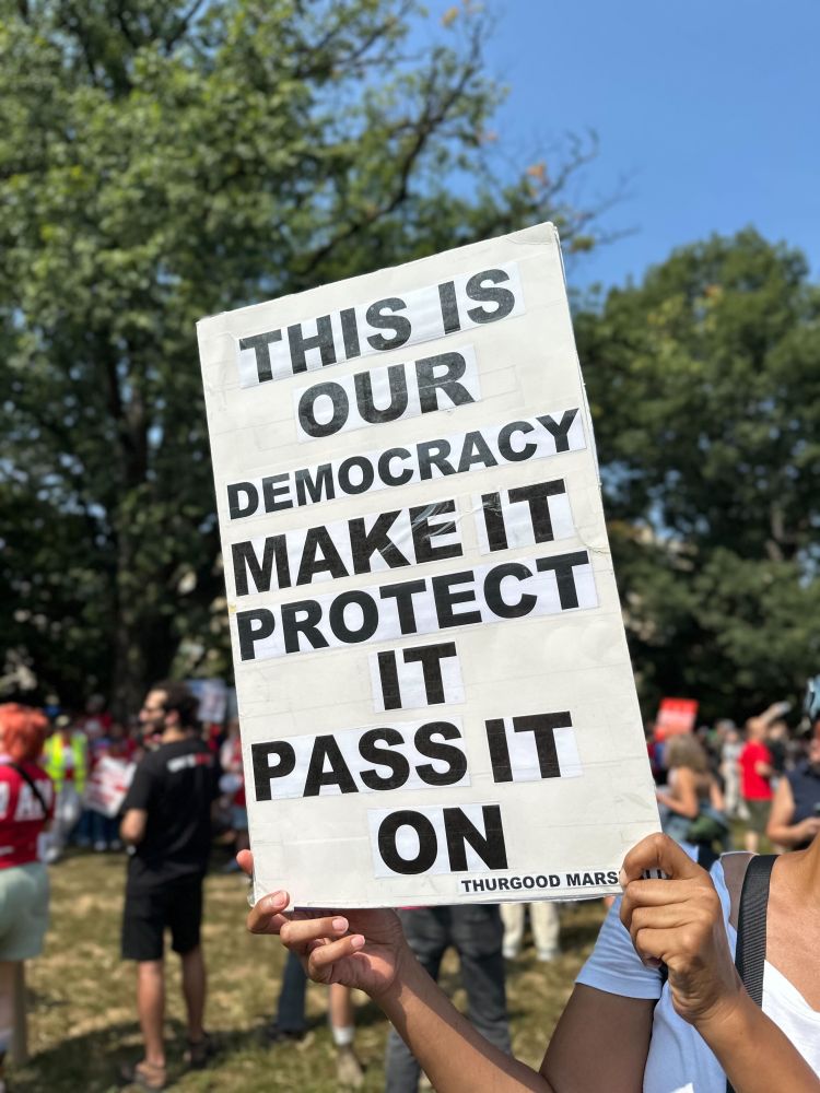 Someone holds up a sign that says, 