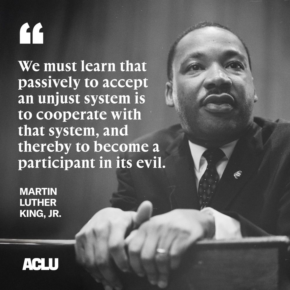 Black and white photo of Martin Luther King, Jr. with quote "We must learn that passively to accept an unjust system is to cooperate with that system, and thereby to become a participant in its evil." the quote is attributed to Martin Luther King, Jr. In the photo, Dr. King is wearing a suit and tie, standing at a podium speaking.