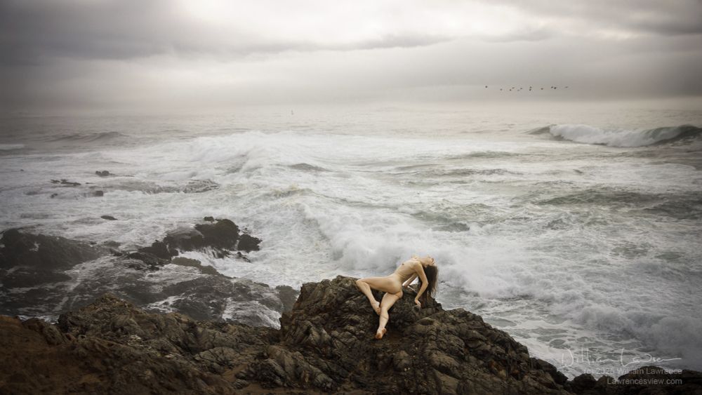 A moody landscape/seascope of a misty day on the northern California coast, with model Frances In Frame posing nude on cliff overlooking rough seas hitting the coast.