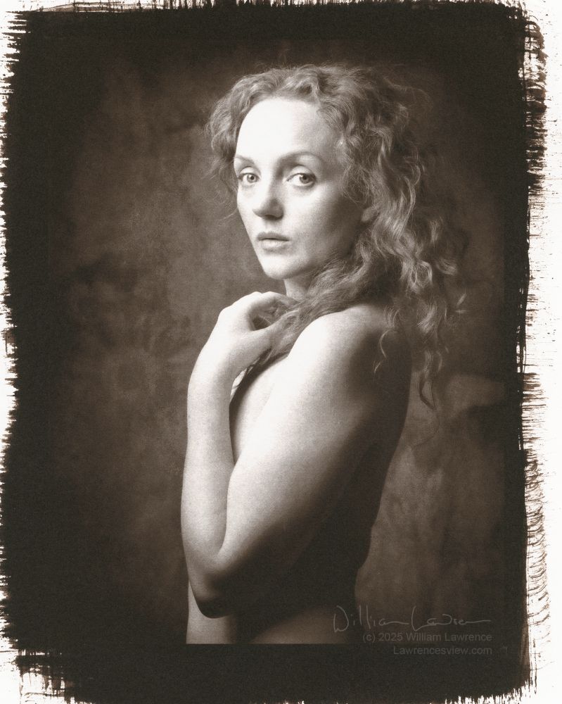 Model Ivory Flame poses nude with body in profile and head turned so eyes engage the viewer. Her arm covers her breast, and holds some of her long hair. This is a gold-toned kallitype, so monochrome with a slight red/purple tone to the photo.