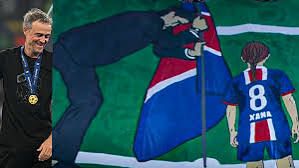 Lo striscione dei tifosi del psg raffigurante un disegno di Luis Enrique che pianta una bandiera in mezzo al campo con la figlia Xana.