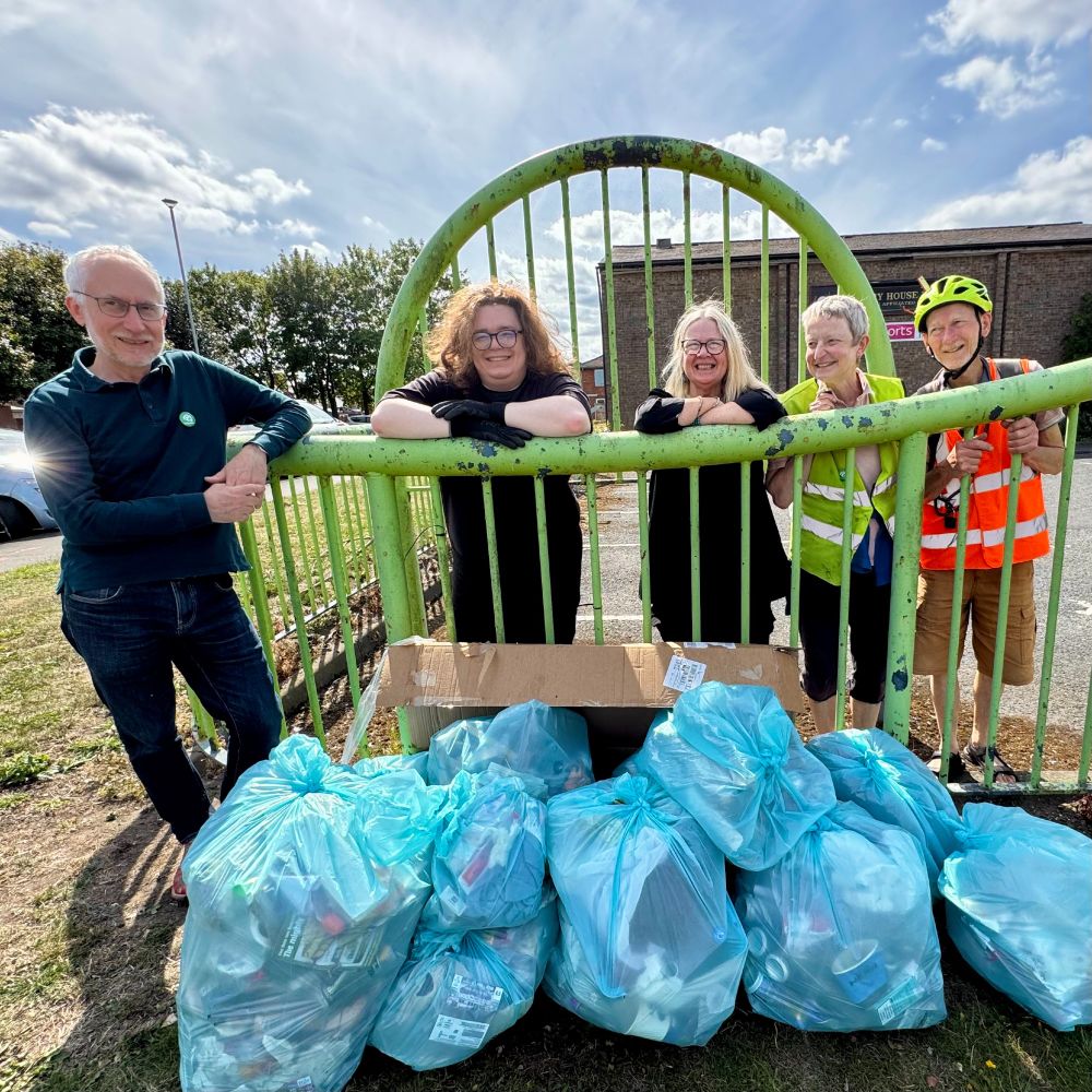 From left to right: Joe, Melissa, Rachel, Ruth and Campbell pose around nine full blue bin bags and some cardboard. They're all smiling!