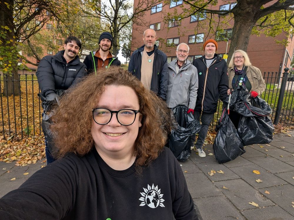 Melissa is smiling in the front with a black jumper with a Green Party logo on it. Behind her is six people: five men and one woman with bin bags and some have litter picks. Everyone has Green Party badges.