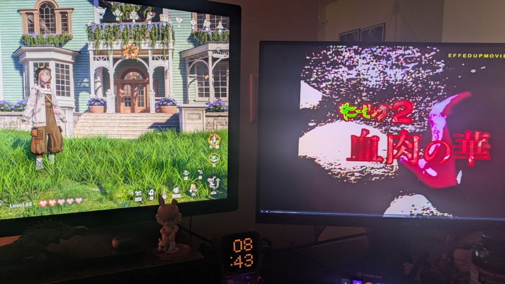 Two computer monitors. One displays a cute house in Infinity Nikki, while the other shows the title card for v-cinema horror movie Guinea Pig 2 Flowers of Flesh and Blood.