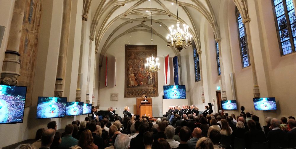 Church-like room full of people listening to a female speaker