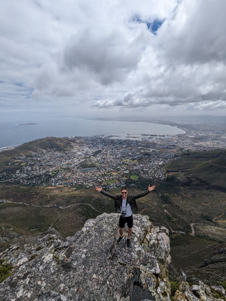 View of Cape Town from Table Mountain with Chris P-K in the foreground holding his hands up to frame the city