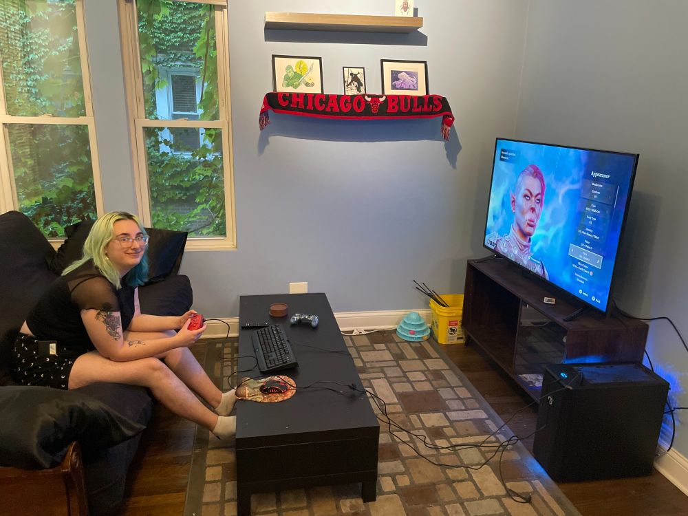 Me in a living room playing bladurs gate 3 on a big TV with a controller