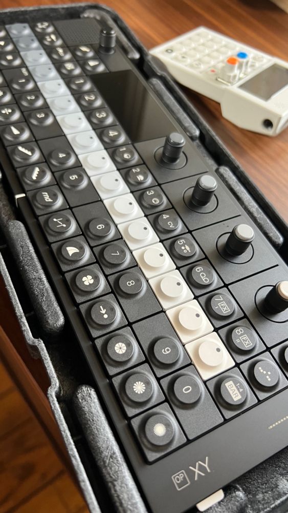 A photo of a grey scale sequencer synthesizer device at an angle-it’s the OP-XY
