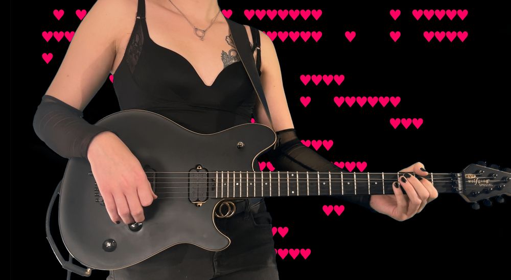 A guitarist holding a black guitar with pink ASCII hearts in the background
