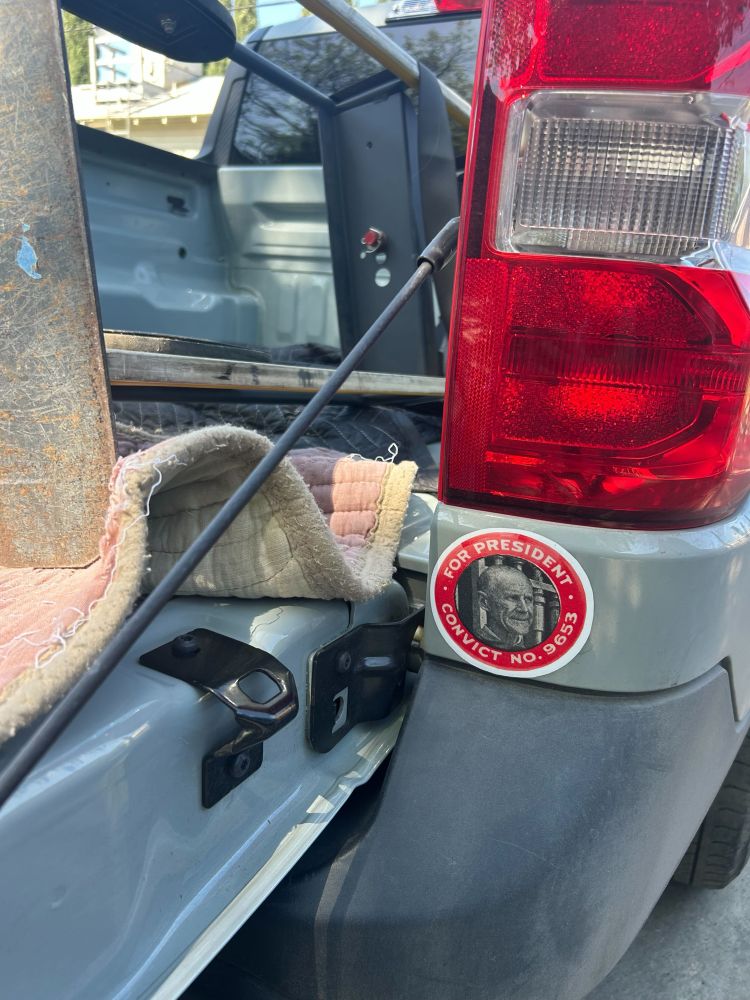Detail of the back of the truck that transported the fridge, with a visible sticker with a photo of Eugene Debs and the text “For President - Convict No. 9653”