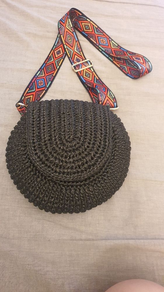검은색 코바늘 탬버린백. 광택 있는 소재의 굵은 실. 무지개색 크로스 스트랩.